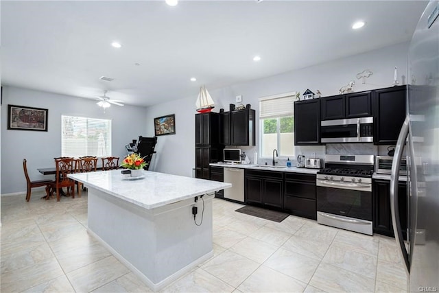 68245 Peladora Rd, Cathedral City, CA 92234 - kitchen with a sink, dark cabinets, stainless steel appliances, a ceiling fan, and a kitchen island