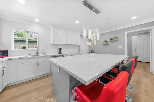 kitchen featuring a center island, a sink, white cabinets, and ornamental molding