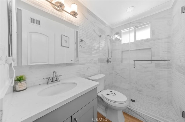 full bath featuring vanity, toilet, a shower stall, visible vents, and ornamental molding