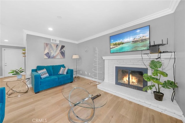 living area featuring a brick fireplace, visible vents, ornamental molding, and wood finished floors