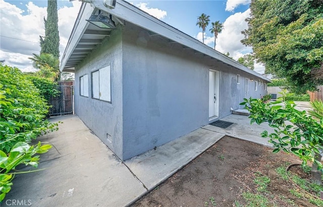 view of property exterior with crawl space, fence, a patio area, and stucco siding