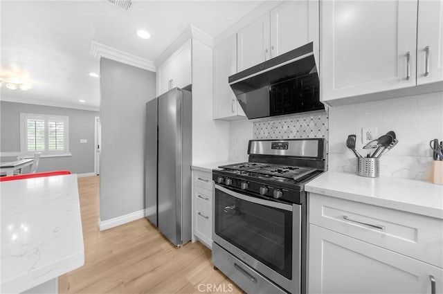 kitchen with appliances with stainless steel finishes, range hood, white cabinets, ornamental molding, and light wood-style flooring