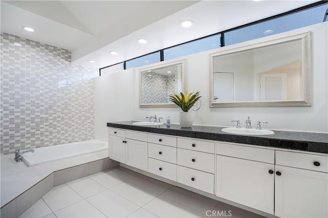 bathroom featuring double vanity, tile patterned floors, a garden tub, and a sink