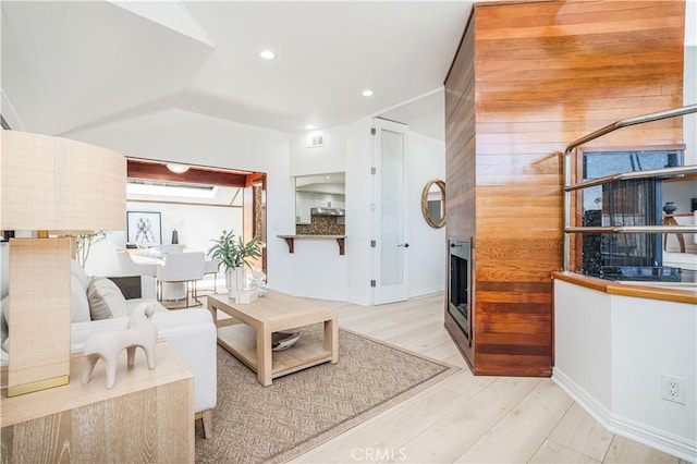 living area with visible vents, a multi sided fireplace, recessed lighting, wood finished floors, and vaulted ceiling