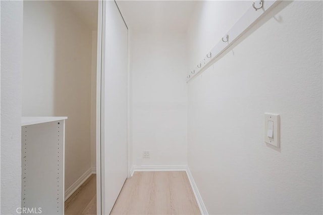walk in closet with light wood finished floors