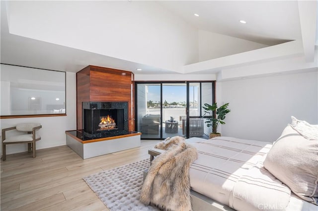 bedroom with a multi sided fireplace, recessed lighting, high vaulted ceiling, and wood finished floors