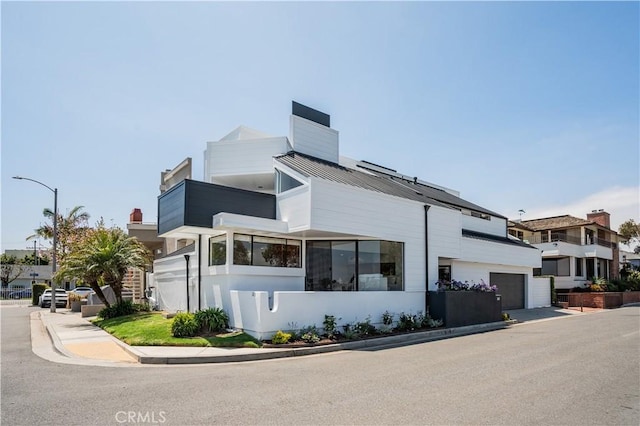 view of property exterior featuring a standing seam roof, a chimney, metal roof, a balcony, and an attached garage