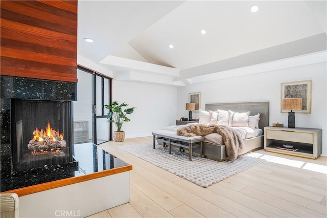 bedroom with recessed lighting, vaulted ceiling, wood finished floors, and a tile fireplace