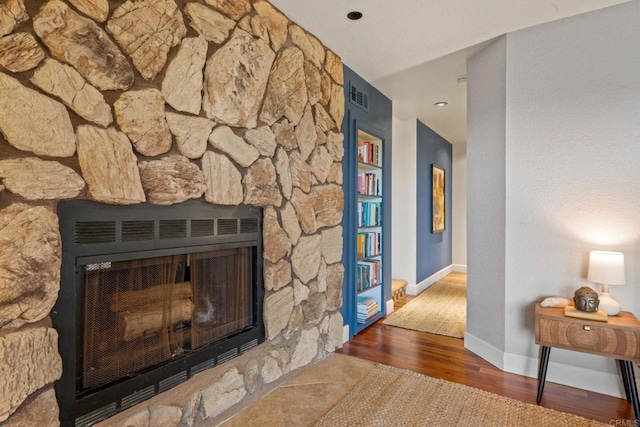 interior details with visible vents, baseboards, wood finished floors, and a fireplace