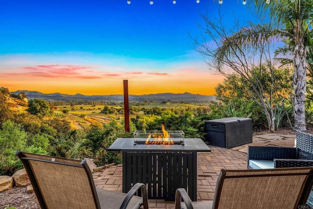 patio terrace at dusk with a fire pit and a mountain view