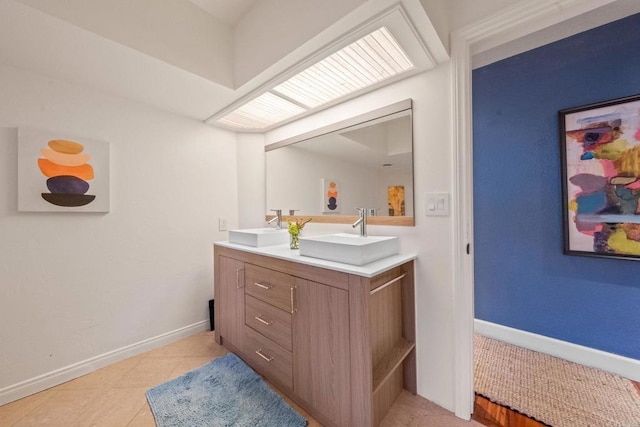 bathroom with double vanity, baseboards, a sink, and tile patterned flooring