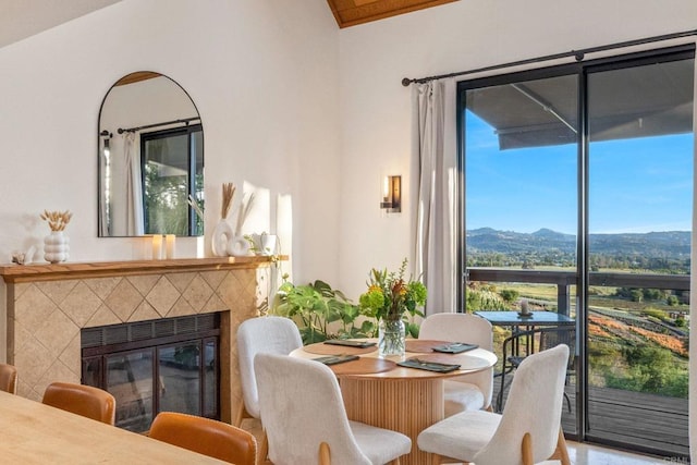 dining space featuring a mountain view, a healthy amount of sunlight, and a tiled fireplace