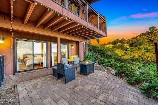 view of patio with an outdoor fire pit and a balcony