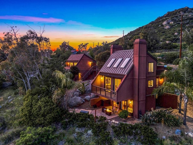 back of property featuring a deck with mountain view, a chimney, and a patio area