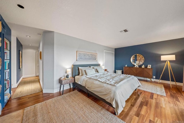 bedroom featuring baseboards, wood finished floors, and visible vents