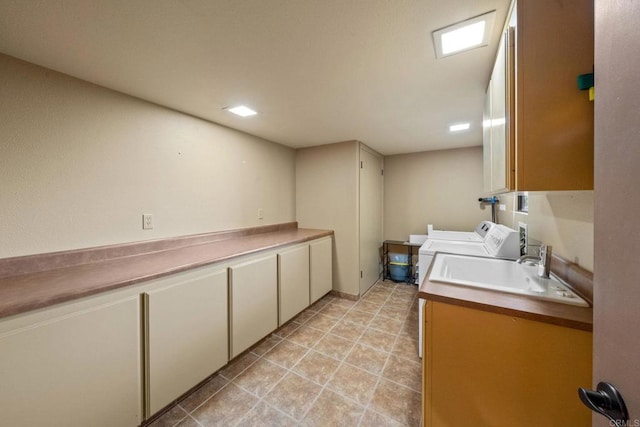clothes washing area with a sink, cabinet space, and washer and dryer