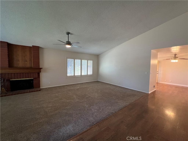 unfurnished living room featuring wood finished floors, a fireplace, baseboards, ceiling fan, and a textured ceiling