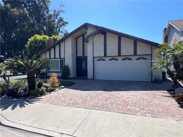 view of front facade featuring a garage, decorative driveway, stucco siding, and a chimney