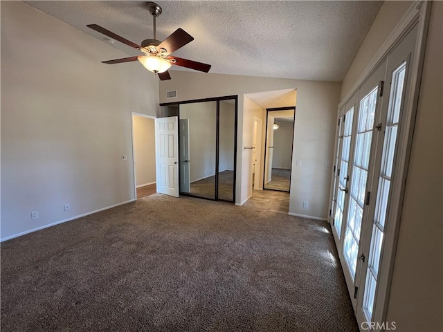 unfurnished bedroom with a textured ceiling, french doors, carpet, vaulted ceiling, and visible vents