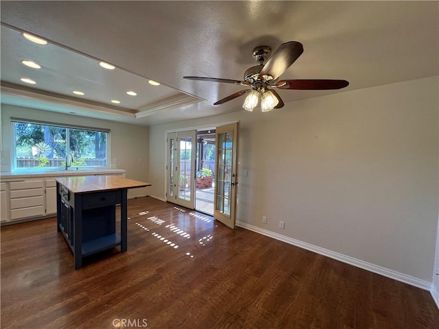 kitchen with baseboards, light countertops, a raised ceiling, white cabinets, and dark wood finished floors