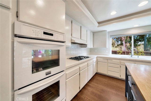 31341 Via Sonora, San Juan Capistrano, CA 92675 - kitchen with dark wood-type flooring, light countertops, under cabinet range hood, white cabinets, and white double oven