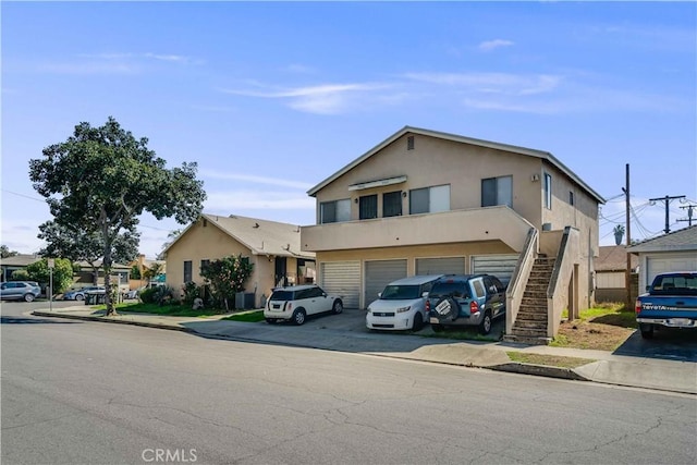 view of front of house featuring stairs, a garage, stucco siding, and driveway