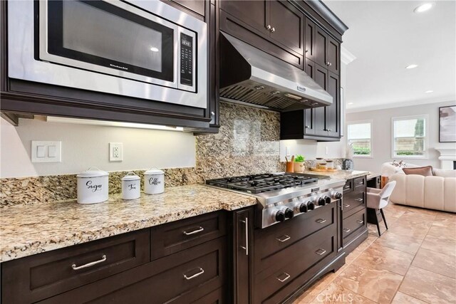 12 Starflower, Lake Forest, CA 92630 - kitchen with appliances with stainless steel finishes, under cabinet range hood, backsplash, open floor plan, and dark brown cabinetry