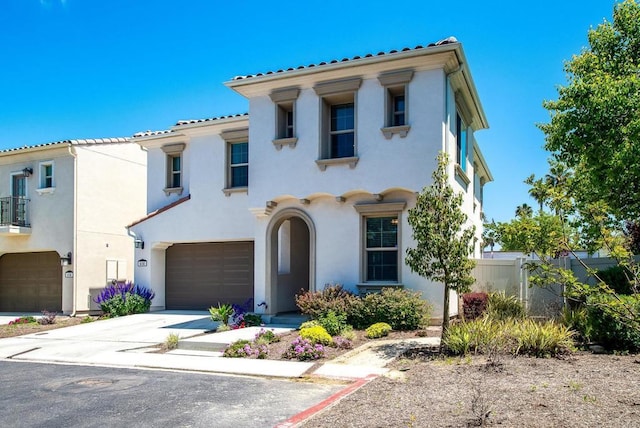mediterranean / spanish home with driveway, a tile roof, fence, an attached garage, and stucco siding