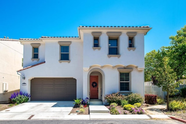 mediterranean / spanish-style house featuring fence, stucco siding, an attached garage, driveway, and a tile roof