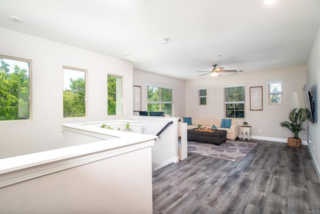 living area with a ceiling fan, baseboards, a healthy amount of sunlight, and wood finished floors
