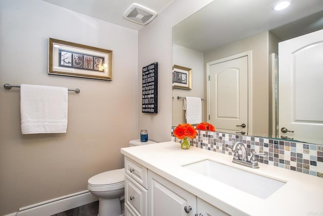 bathroom featuring vanity, toilet, baseboards, backsplash, and visible vents