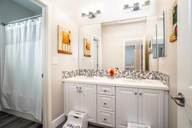 bathroom with a sink, curtained shower, backsplash, and double vanity
