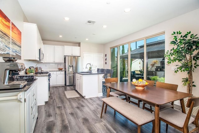 kitchen with appliances with stainless steel finishes, a sink, dark wood finished floors, white cabinetry, and visible vents