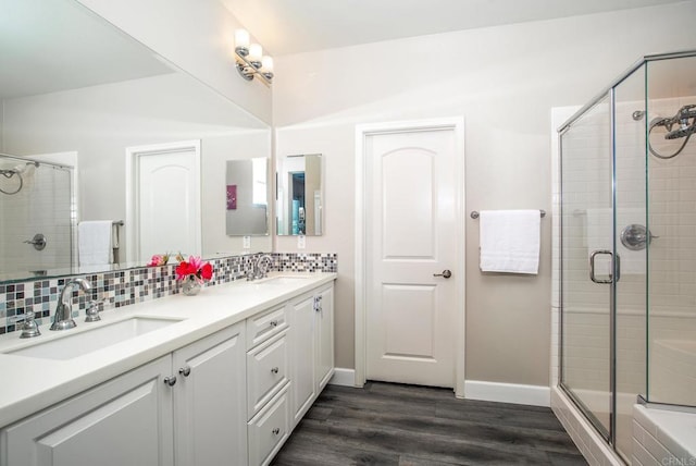 bathroom featuring wood finished floors, a shower stall, a sink, and tasteful backsplash