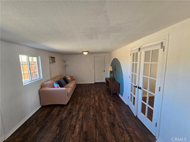 living area featuring a textured ceiling, baseboards, french doors, and wood finished floors