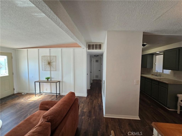 living room featuring dark wood-style flooring, a textured ceiling, and visible vents