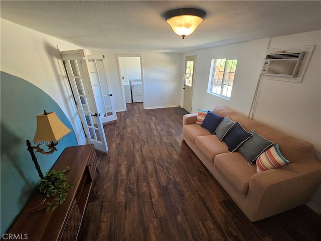 living area with a textured ceiling, french doors, a wall unit AC, wood finished floors, and washer and clothes dryer