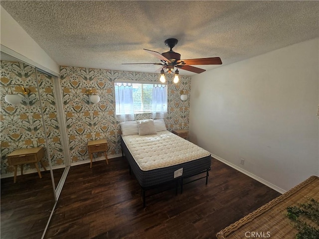 bedroom with ceiling fan, a textured ceiling, dark wood finished floors, wallpapered walls, and baseboards