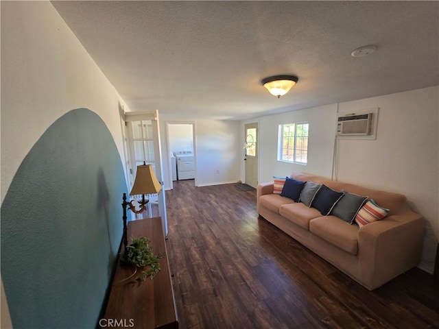 living room featuring a textured ceiling, dark wood finished floors, baseboards, and a wall mounted air conditioner