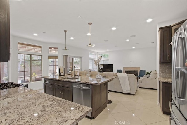 kitchen featuring a sink, appliances with stainless steel finishes, dark brown cabinets, and light stone countertops