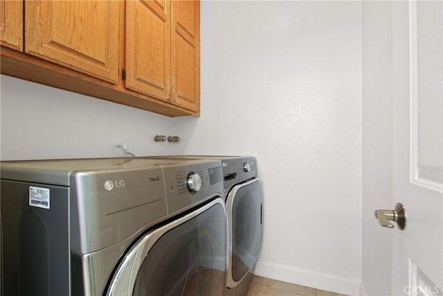 laundry room featuring cabinet space, independent washer and dryer, baseboards, and light tile patterned flooring