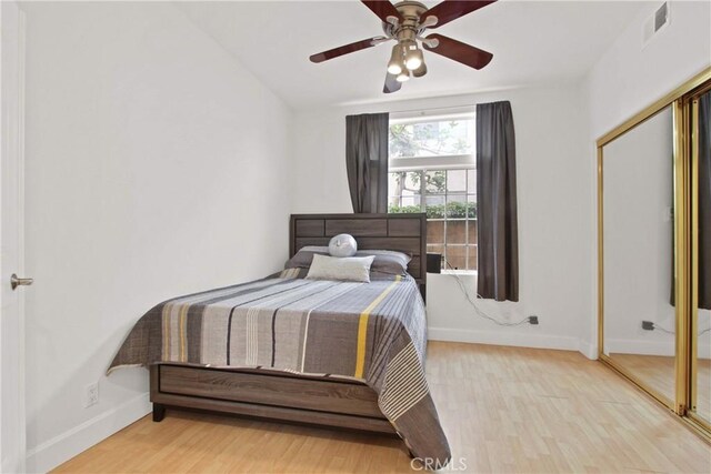bedroom featuring baseboards, a ceiling fan, wood finished floors, and visible vents