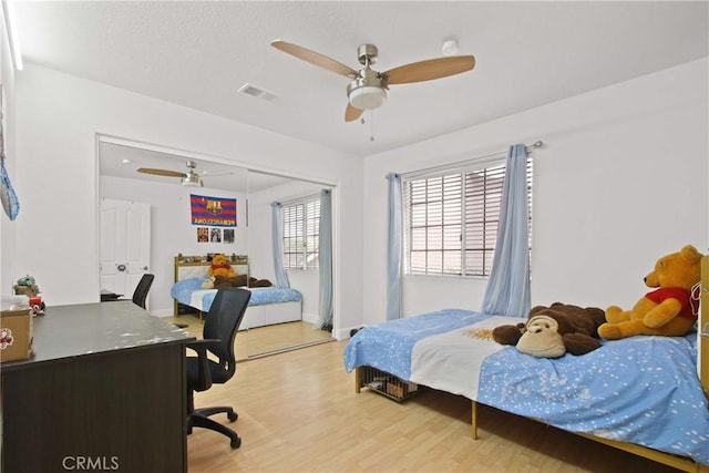 bedroom featuring light wood-style floors, a ceiling fan, a closet, and visible vents