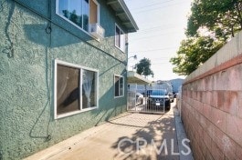 view of side of home with stucco siding and fence
