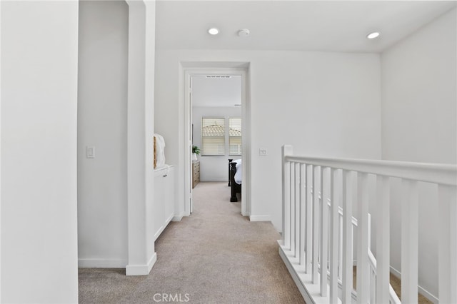 hallway featuring recessed lighting, baseboards, an upstairs landing, and light carpet