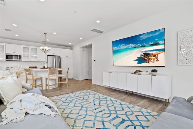 living room with recessed lighting, visible vents, and light wood-style flooring