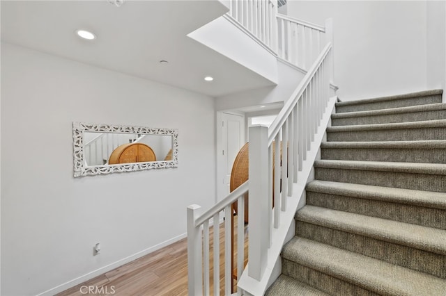 stairway featuring recessed lighting, baseboards, and wood finished floors