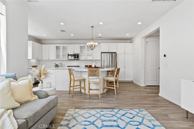 living room with light wood-style flooring, radiator, recessed lighting, baseboards, and visible vents