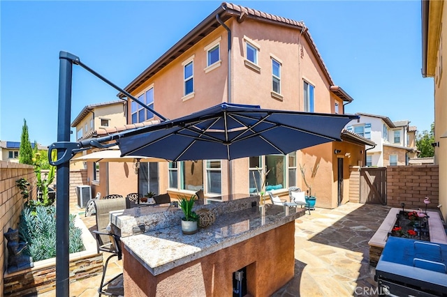 back of house with fence, a patio, stucco siding, outdoor dry bar, and a gate
