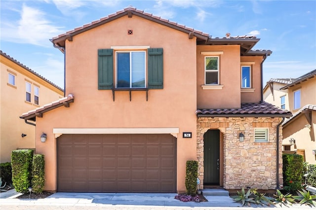 mediterranean / spanish-style home featuring a garage, a tiled roof, stucco siding, and stone siding